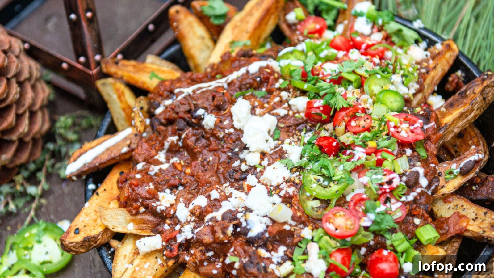 12 Epic Chili Recipes for Game Day Crowd-Pleasing Flavor 4 Loaded fries inspired by the best chili recipes, topped with diced tomatoes, jalapeños, cheese, sour cream, and chopped herbs on a rustic wooden table.