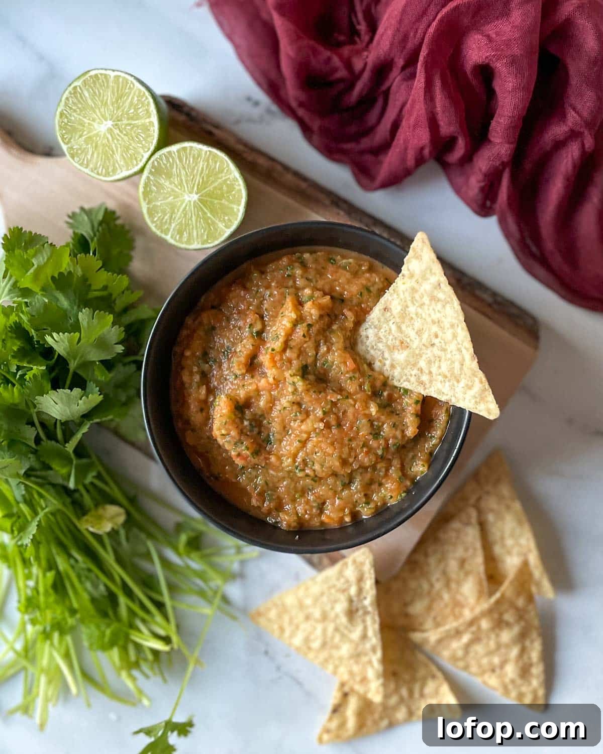 Tangy Pineapple Habanero Salsa Recipe for Grilling and Tacos 2 A bowl of pineapple habanero salsa sits on a rustic wooden cutting board surrounded by limes, cilantro, and tortilla chips.