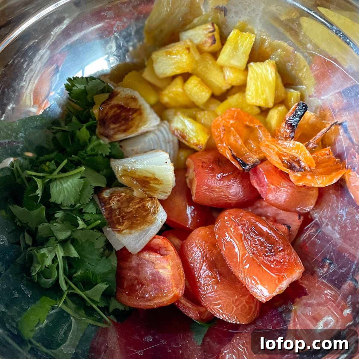 Tangy Pineapple Habanero Salsa Recipe for Grilling and Tacos 10 The roasted ingredients for pineapple habanero salsa are shown in a metal bowl.