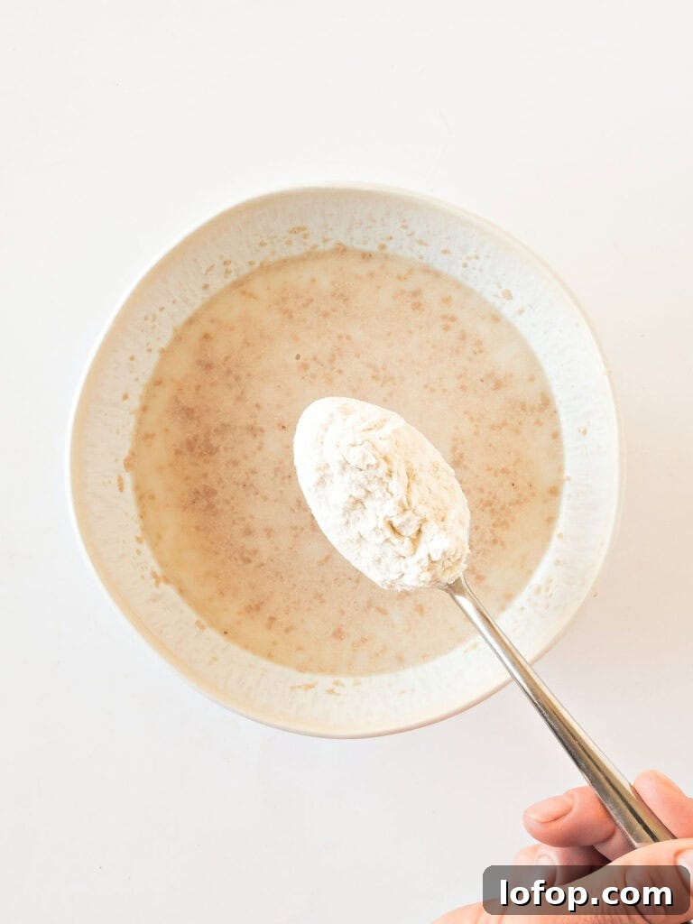 Perfectly Soft Homemade Burger Buns Recipe 5 Adding flour to a white bowl with yeast and water.