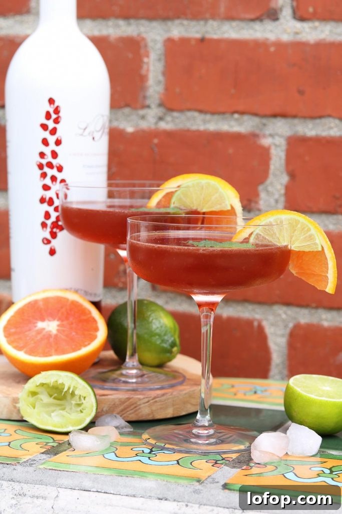 Two Pomerita Cocktails with orange, lime and ice against brick wall