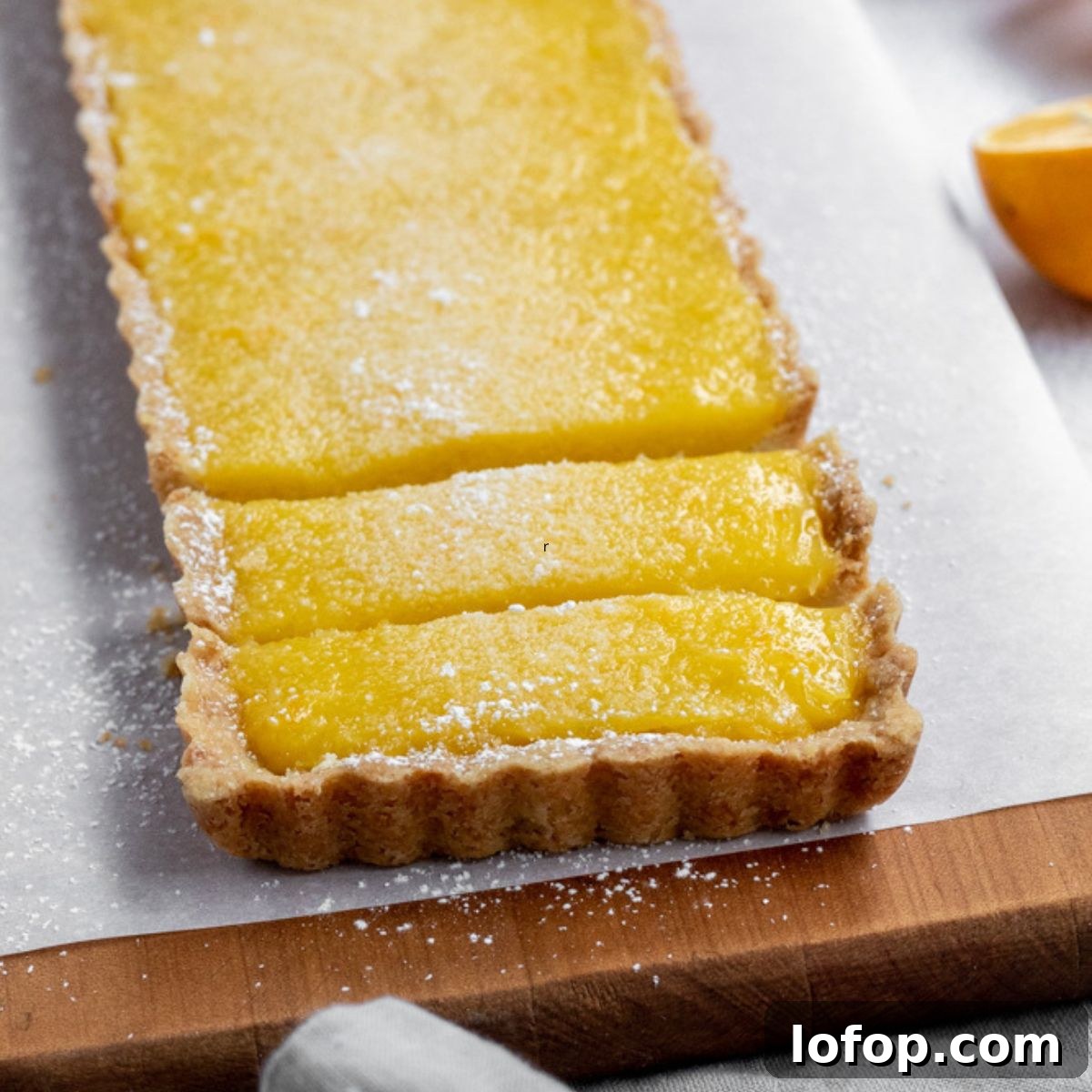 Meyer Lemon and Olive Oil Tart Recipe for Bright, Silky Dessert 2 A rectangular shaped lemon tart sliced.