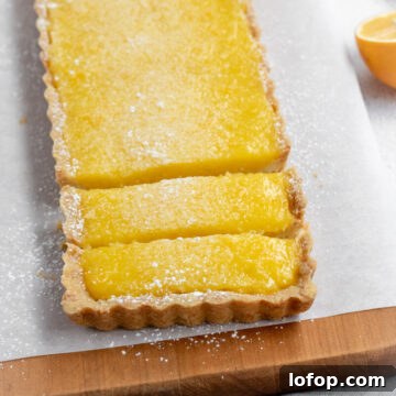 A bright yellow lemon tart cut into pieces.