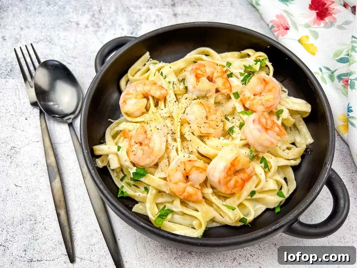 31 Irresistible Seafood Dinners to Add Fish to Your Weekly Menu 12 A bowl of olive garden creamy shrimp alfredo pasta served in a black bowl with a spoon.