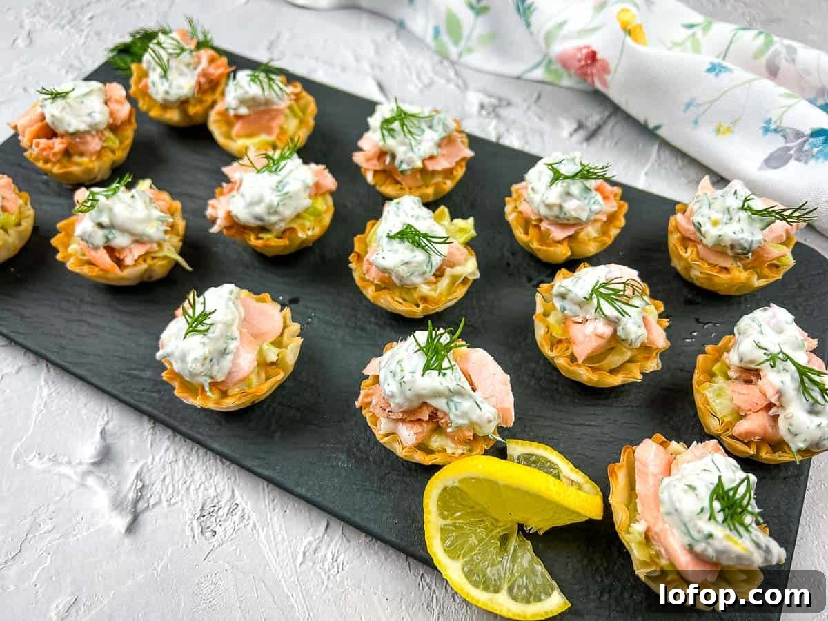 31 Irresistible Seafood Dinners to Add Fish to Your Weekly Menu 23 Salmon & Leek Phyllo Tartlets with lemon wedges on a black plate.