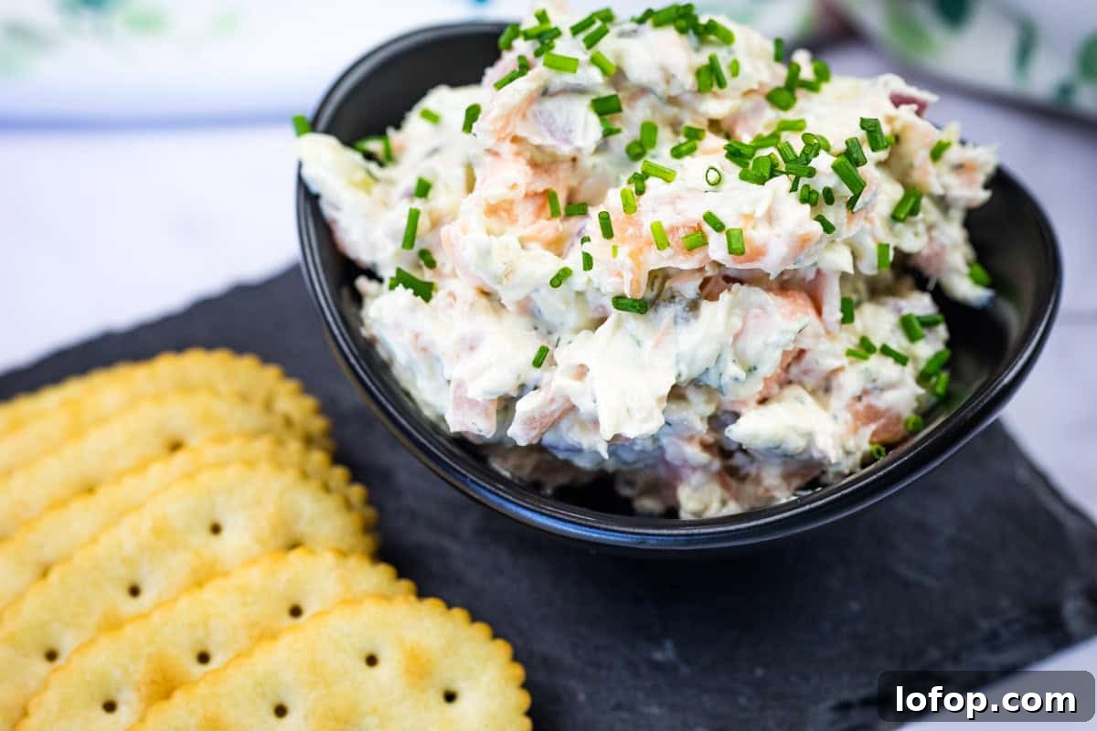 31 Irresistible Seafood Dinners to Add Fish to Your Weekly Menu 9 Bowl of smoked salmon spread garnished with chopped chives next to crackers on a slate platter.