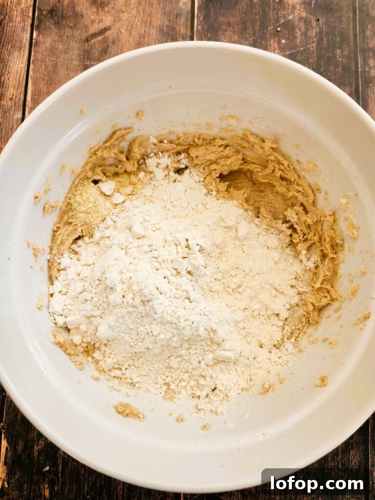 adding flour to almond cookie dough