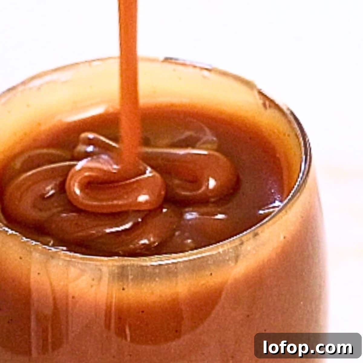 Shiny homemade caramel sauce in a glass cup
