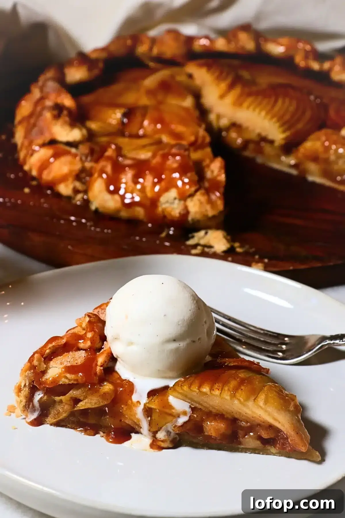 a slice of caramel apple galette with caramel sauce and vanilla ice cream
