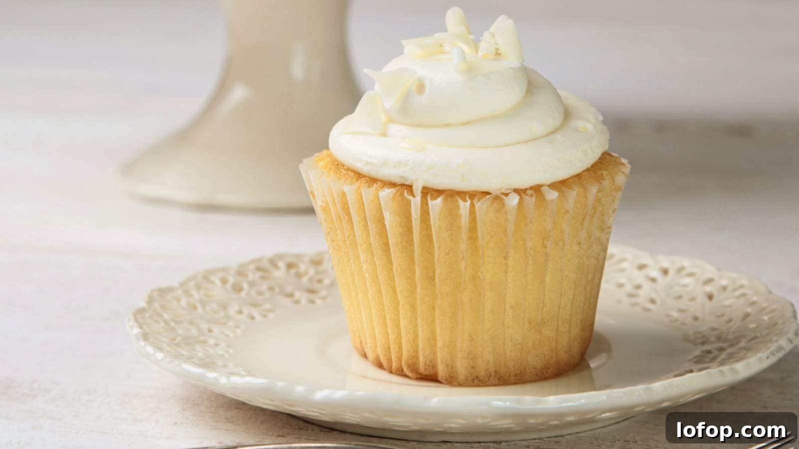 15 Decadent Low-Calorie Desserts That No One Will Suspect Are Light 11 Vanilla cupcake with frosting on white china plate.