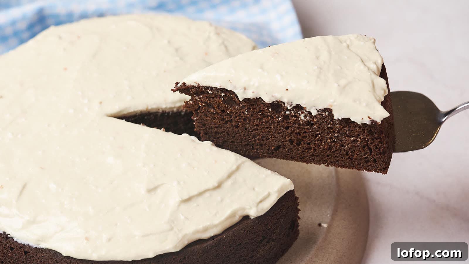 15 Decadent Low-Calorie Desserts That No One Will Suspect Are Light 7 A slice of chocolate cake with white frosting being lifted from the whole cake.