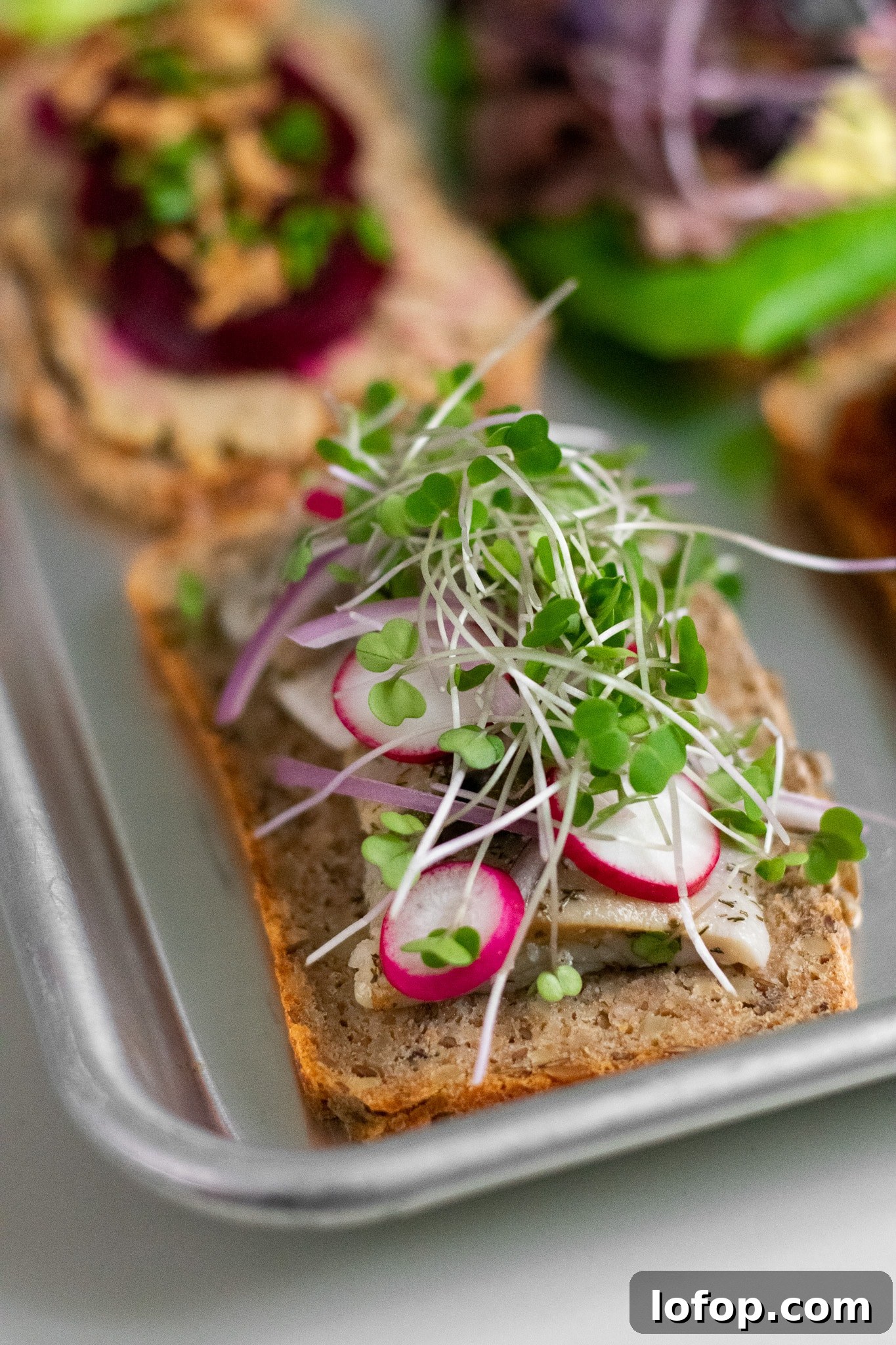Smørrebrød: Traditional Danish Open-Faced Sandwich Recipes 2 A rye bread open faced sandwich topped with herring, onion, radish, and micro greens.