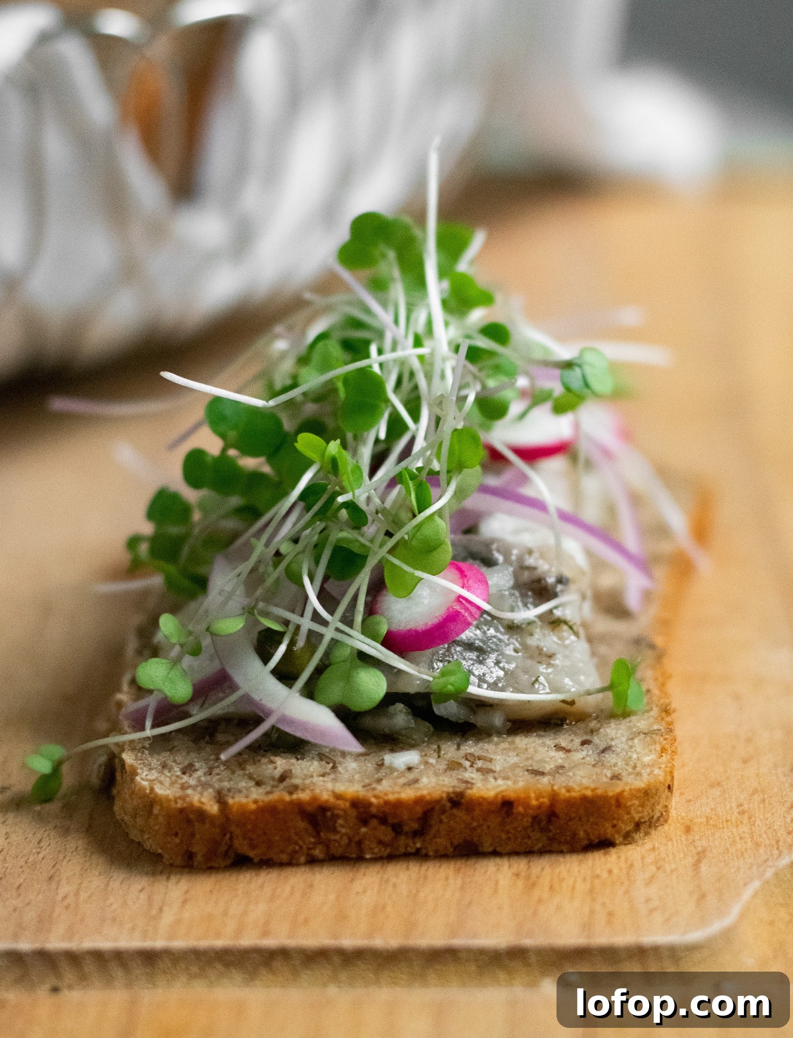 Smørrebrød: Traditional Danish Open-Faced Sandwich Recipes 11 A rye bread open faced sandwich topped with herring, onion, radish, and micro greens.