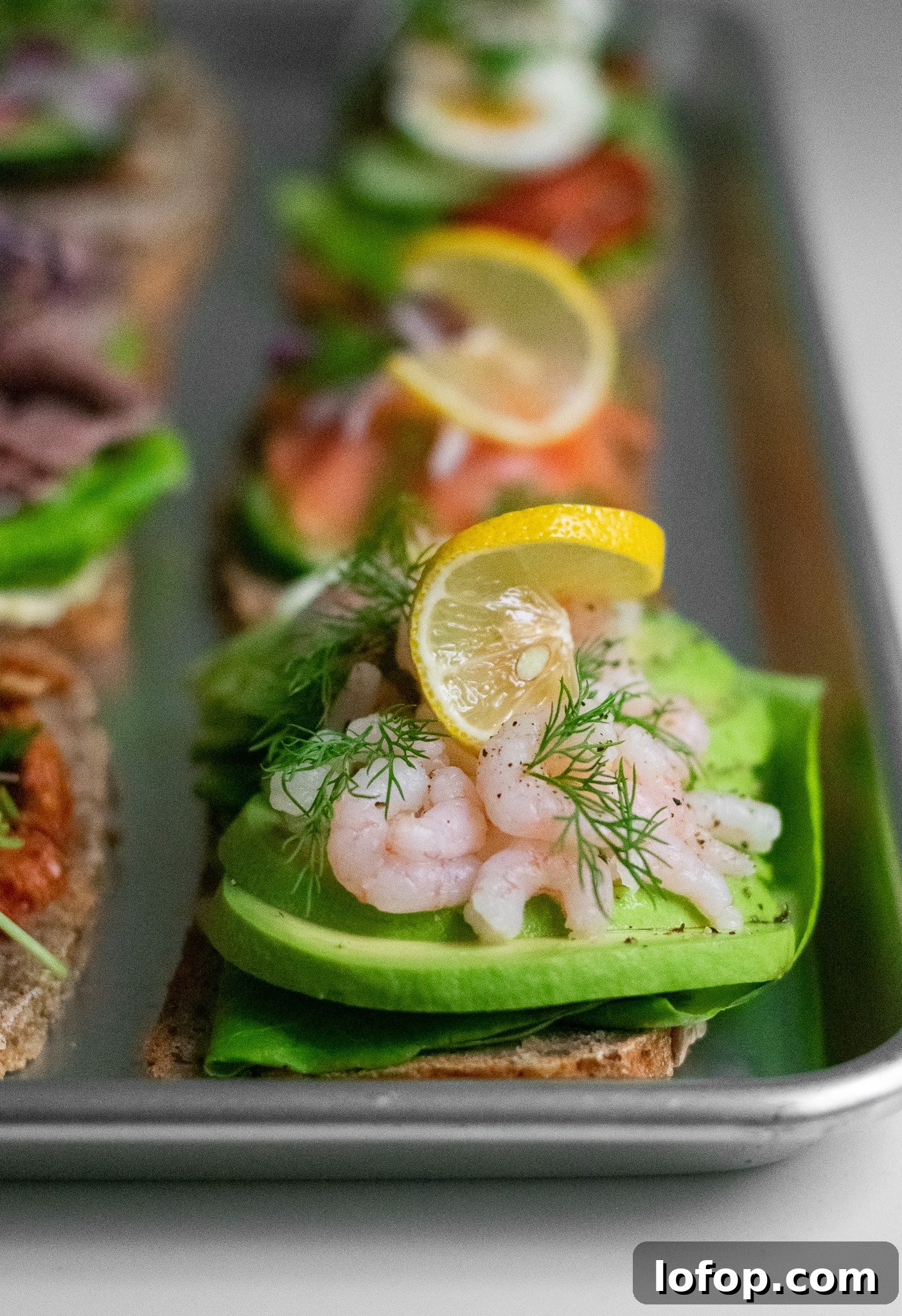 Smørrebrød: Traditional Danish Open-Faced Sandwich Recipes 4 A rye bread open faced sandwich topped with lettuce, avocado, baby shrimp, dill, and lemon.