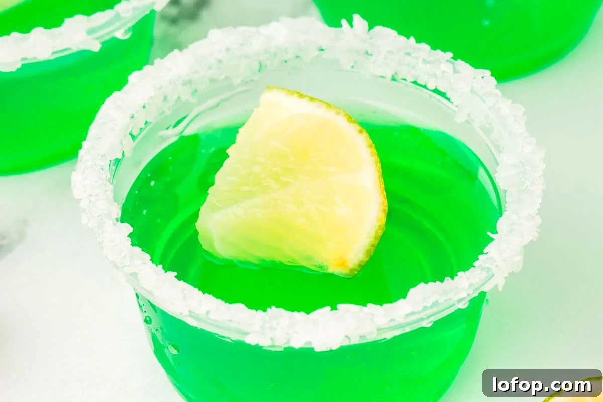 29 Jello Shot Recipes to Kick Off Any Party Night 22 A lime margarita in a glass with a slice of lime and jello shots.