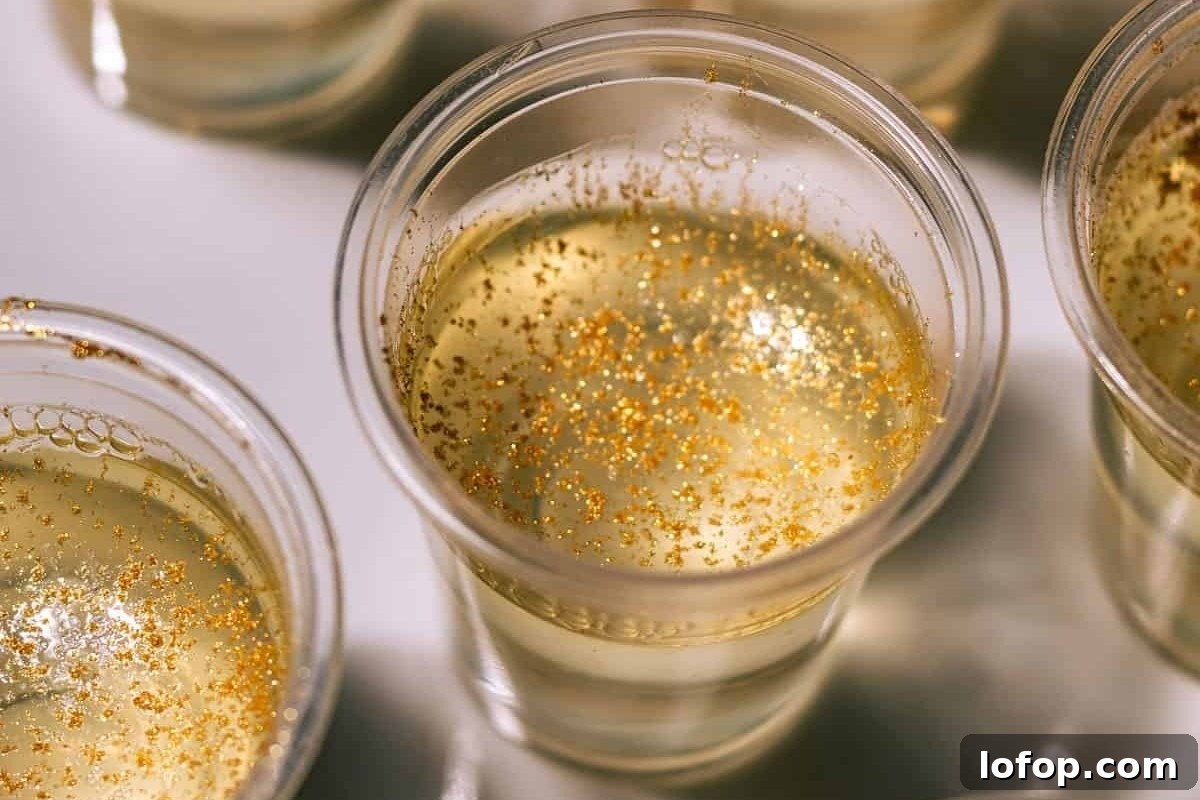 29 Jello Shot Recipes to Kick Off Any Party Night 27 Four cups of champagne with gold sprinkles served at a New Year's eve party.