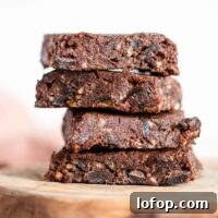 Vegan No-Bake Chocolate Brownies — Quick Raw Dessert Recipe 9 A close up of a stack of 4 raw brownies on a cutting board.